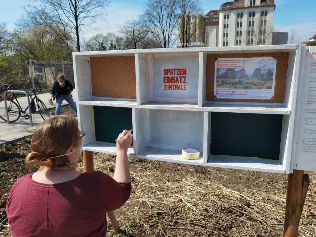 Eine Frau an der Infotafel im offenen Garten am Alberthafen.