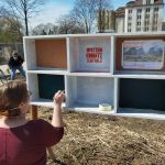 Eine Frau an der Infotafel im offenen Garten am Alberthafen.